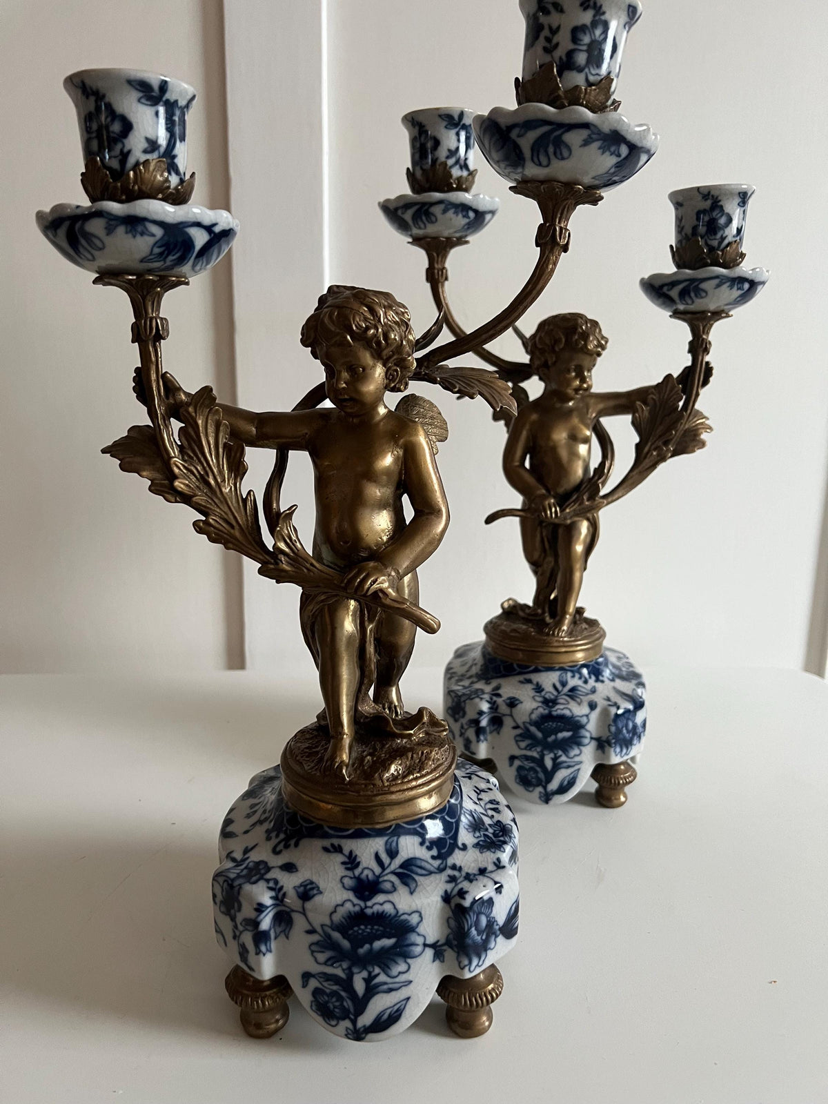 Ornate Cherub Candelabra Pair – Gilt Metal with Blue & White Porcelain Bases